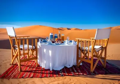 a table and two chairs in the desert at Sahary Tafilalt Luxury Camp in Merzouga