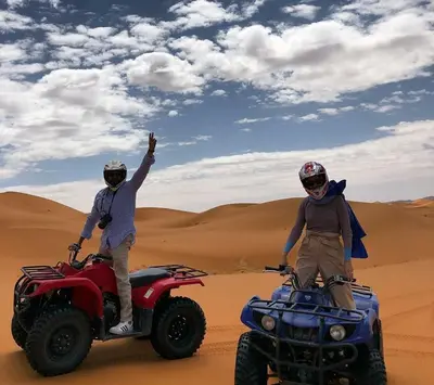 two men standing on atvs in the desert at Sahary Tafilalt Luxury Camp in Merzouga