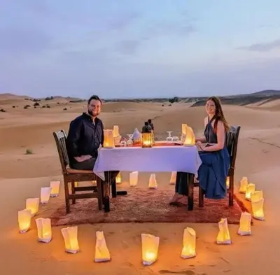 a man and woman sitting at a table in the desert at Sahary Tafilalt Luxury Camp in Merzouga