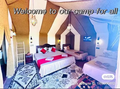 a bedroom with two beds and a sign welcome to our camp for all at Sahary Tafilalt Luxury Camp in Merzouga