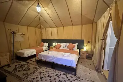 a bedroom with two beds in a tent at Host Luxury Camp in Merzouga