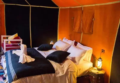 two beds with black and white pillows in a room at Host Luxury Camp in Merzouga