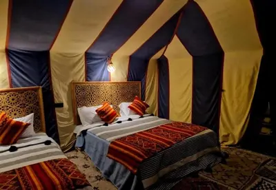 a bedroom with two beds in a tent at Host Luxury Camp in Merzouga
