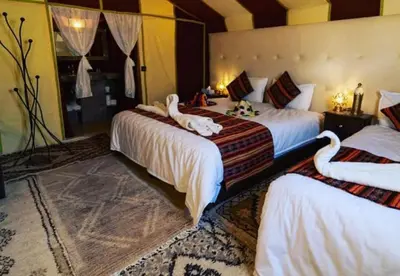 a bedroom with two beds with swans on them at Host Luxury Camp in Merzouga