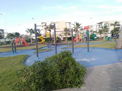 a park with a playground with slides and swings at Appartement dans une résidence balnéaire à Sidi Rehal in Oulad Akkou