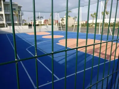 a view of a baseball field from behind a fence at Appartement dans une résidence balnéaire à Sidi Rehal in Oulad Akkou