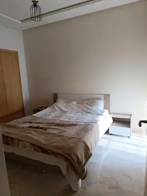 a white bedroom with a bed in a room at Appartement dans une résidence balnéaire à Sidi Rehal in Oulad Akkou