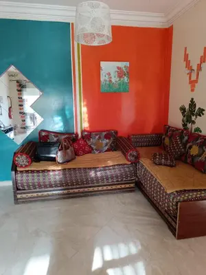 a couch in a living room with orange walls at Appartement dans une résidence balnéaire à Sidi Rehal in Oulad Akkou