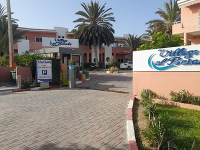 a building with a sign in front of a street at Village al baraka in Oulad Akkou