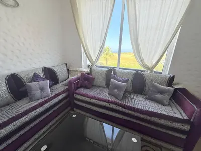 a couch with pillows sitting in front of a window at Marina Asilah golf, tennis pool in Oulad Akkou