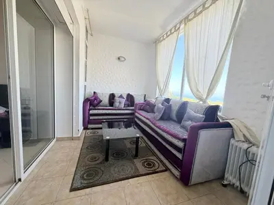 a living room with a purple couch and a window at Marina Asilah golf, tennis pool in Oulad Akkou
