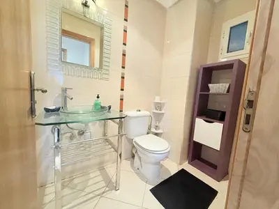 a bathroom with a toilet and a glass sink at Marina Asilah golf, tennis pool in Oulad Akkou