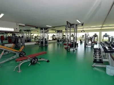 a gym with a green floor and machines in it at Marina Asilah golf, tennis pool in Oulad Akkou