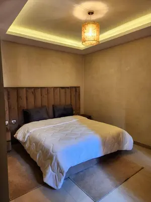 a bedroom with a large white bed and a chandelier at Appartement de Pause Intérieure in Oulad Akkou