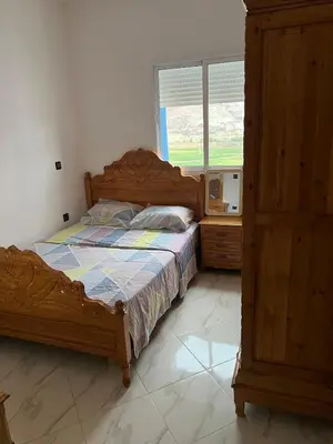 a bedroom with a wooden bed and a window at Appartement in Oulad Akkou