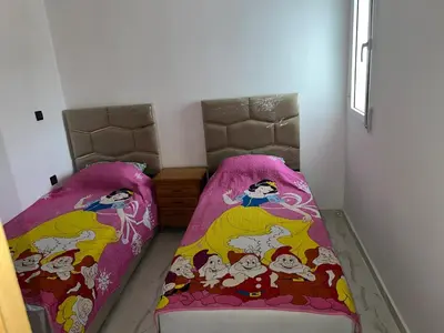 two beds in a room with pink sheets at Appartement in Oulad Akkou