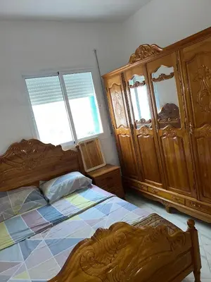 a bedroom with two beds and wooden cabinets at Appartement in Oulad Akkou