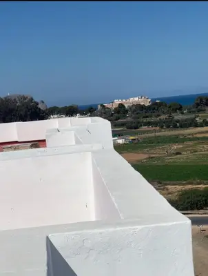 a white building with the ocean in the background at Appartement in Oulad Akkou