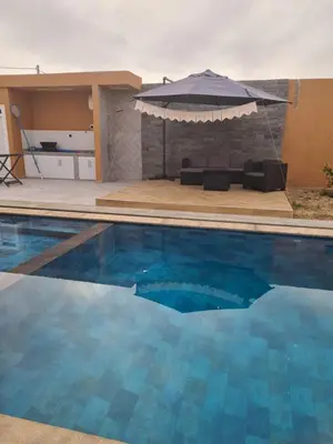 a swimming pool with an umbrella and a couch at Villa avec piscine privée in Oulad Akkou