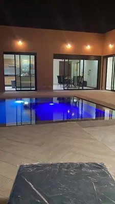 a swimming pool with blue lights in a house at Villa avec piscine privée in Oulad Akkou