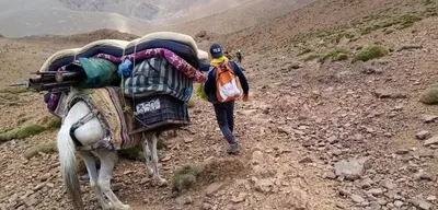 a man walking on a trail with a horse on a mountain at Almarkaz Assiyahi