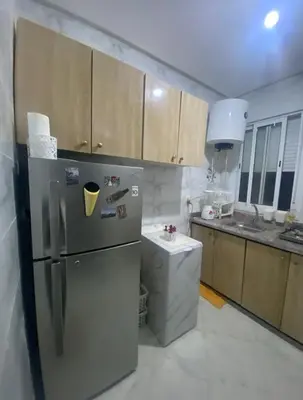 a kitchen with a stainless steel refrigerator and wooden cabinets at Appartement a louer meknes in Meknès