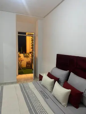 a living room with a bed with red and white pillows at Appartement a louer meknes in Meknès