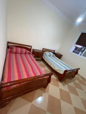 a bedroom with two beds and a checkered floor at Saidia in Oulad Akkou