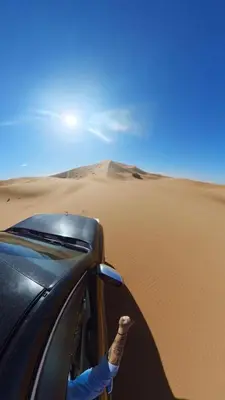a person sticking their hand out of a car in the desert at desertcamp in Merzouga