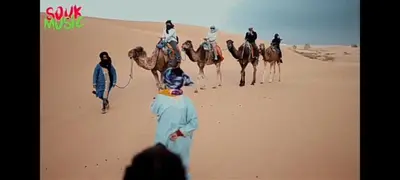 a group of people riding camels in the desert at desertcamp in Merzouga