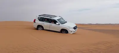 a white van driving through the sand in the desert at desertcamp in Merzouga