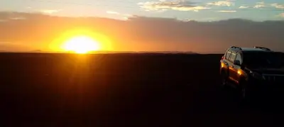 a truck parked in front of a sunset at desertcamp in Merzouga