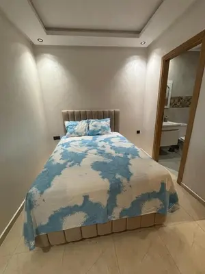 a bedroom with a bed with a blue and white comforter at Chambre, appartement Anas in Oulad Akkou