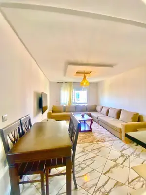 a living room with a table and a couch at Maison Hijaz in Oulad Akkou