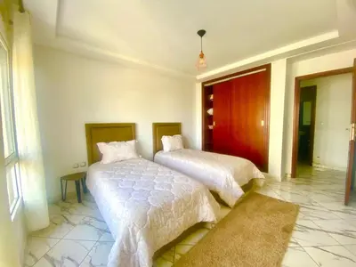 a bedroom with two beds with white sheets and a rug at Maison Hijaz in Oulad Akkou