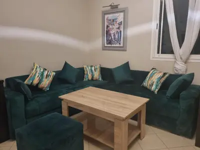 a living room with a green couch and a wooden table at Villa skhirat swimming pool in Oulad Akkou