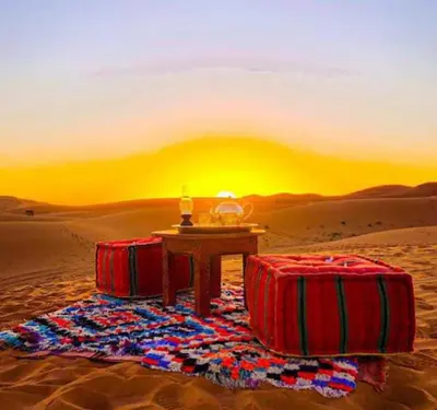 a table in the middle of the desert with two red suitcases at lion Desert luxury Camp in Merzouga