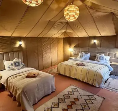 a bedroom with two beds in a tent at lion Desert luxury Camp in Merzouga