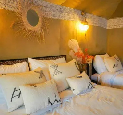 two beds in a room with white pillows at lion Desert luxury Camp in Merzouga