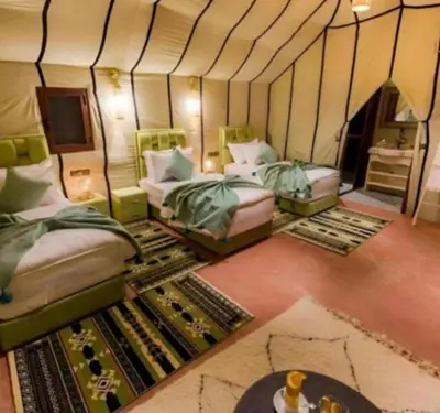 a room with two beds in a tent with a rug at lion Desert luxury Camp in Merzouga
