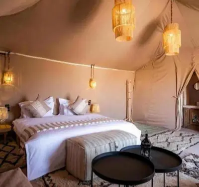 a bedroom with a large white bed and two tables at lion Desert luxury Camp in Merzouga