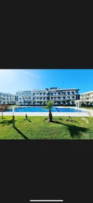 a large apartment building with a palm tree in front of it at Appartement in Oulad Akkou