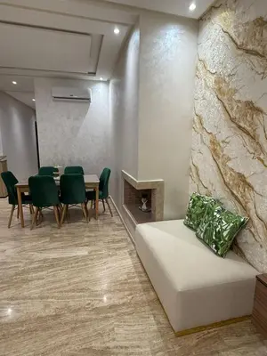 a dining room with a table and green chairs at Appartement in Oulad Akkou