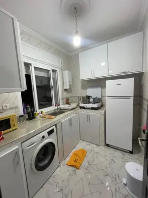 a kitchen with white cabinets and a washer and dryer at Cala iris in Oulad Akkou