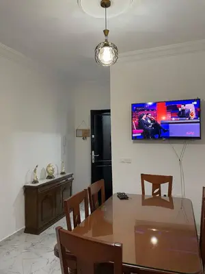 a dining room with a table and a tv on the wall at Cala iris in Oulad Akkou