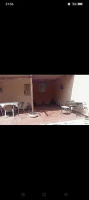 two pictures of a patio with two picnic tables at Cabanon à louer à Mohammedia in Oulad Akkou