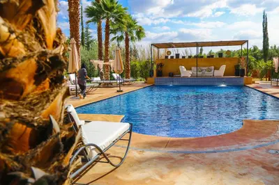 a swimming pool with palm trees and a villa at Villa Palmyra, 8 suites et piscine chauffée in Marrakech