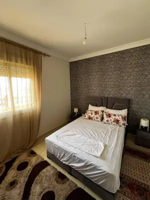 a bedroom with a white bed with pillows and a window at appartement Marrakech in Oulad Akkou