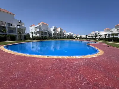 a large blue swimming pool in front of some buildings at RESIDENCE SAIDIA AGDAD ap1 in Oulad Akkou