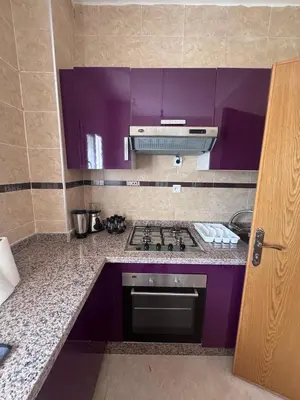 a purple kitchen with a stove and purple cabinets at RESIDENCE SAIDIA AGDAD ap1 in Oulad Akkou